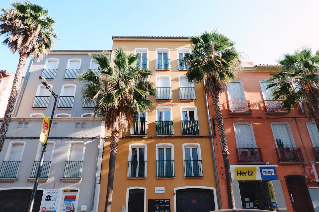 Vibrant apartment buildings with palm trees lining a sunny street exterior, perfect for travel and urban themes.